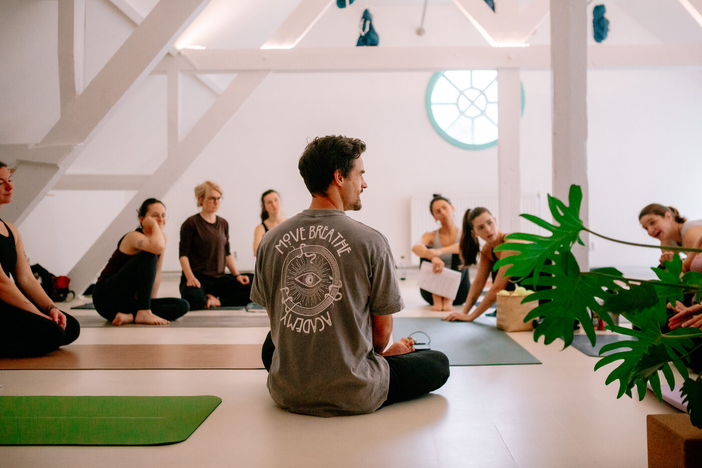 Nils sitzt im Schneidersitz vor einer Yoga-Gruppe